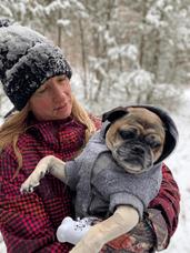 Dr. Durzi holding her pug in a winter forest.