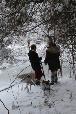 Two people in a winter season forest, walking a pug.